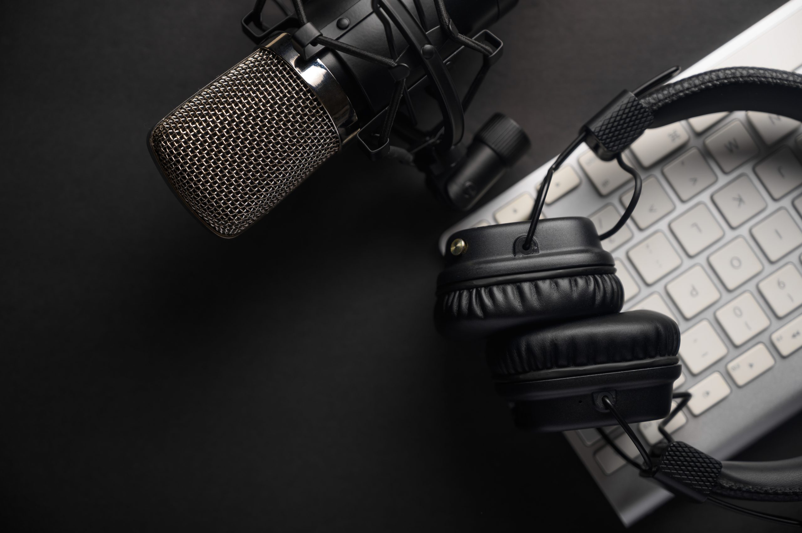 Plano, micrófono de estudio con auriculares profesionales en un teclado de PC. Negro sobre un fondo negro. Podcasts, radio, transmisiones, blogs, trabajar con sonido, grabar pistas